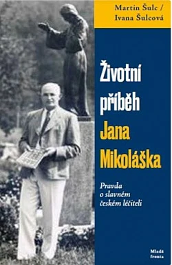 Portrét Jana Mikoláška stojícího vedle sochy.