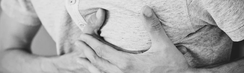 Muž drží ruce na hrudi při bolesti srdce