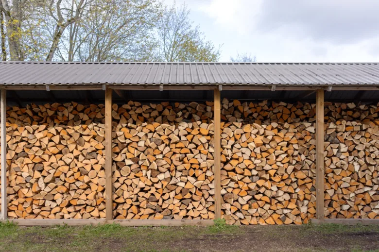 Správně uskladněné dřevo v dřevníku pod střechou venku.