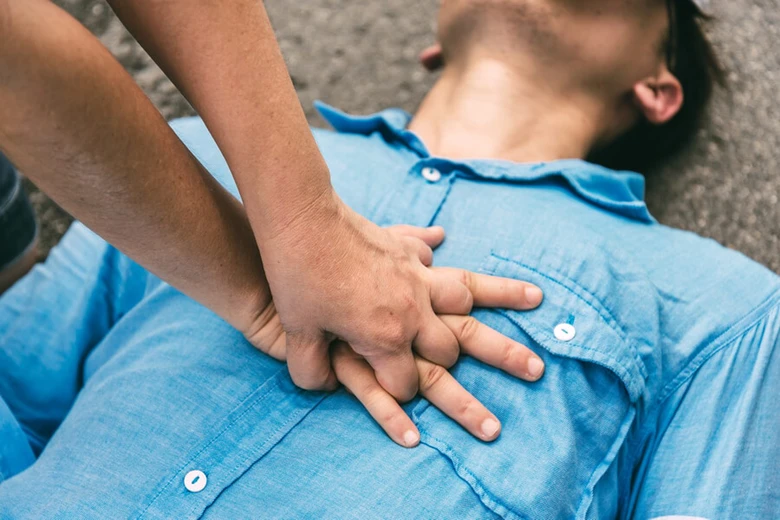 Dvě ruce provádějí správné komprese hrudníku při resuscitaci.
