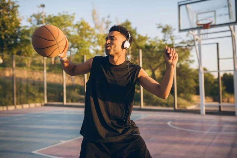 Muž hraje basketbal venku s náušnicemi na uších.