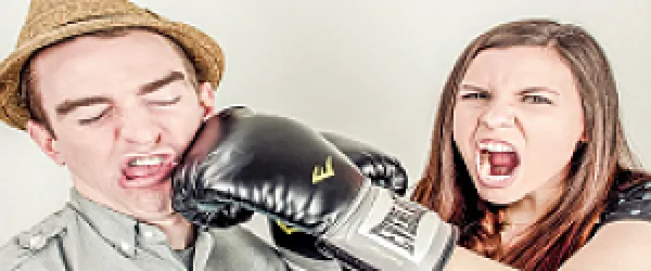 Žena v boxerských rukavicích pěstí muže, který trpí.