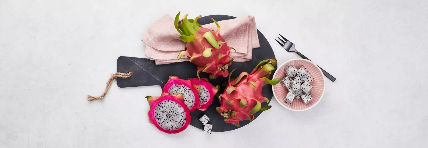 Celé i nakrájené pitahajie na tmavém podnose s lžící.