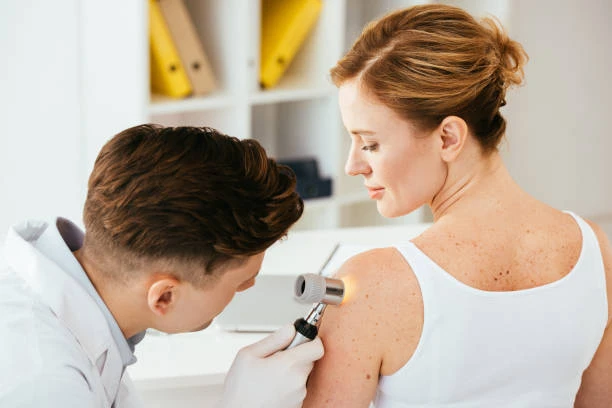 Dermatolog zkoumá znaménko na kůži pomocí derooskopu.