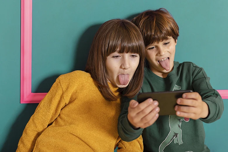 Dva děti se dívají na tablet s výraznými tvářemi.