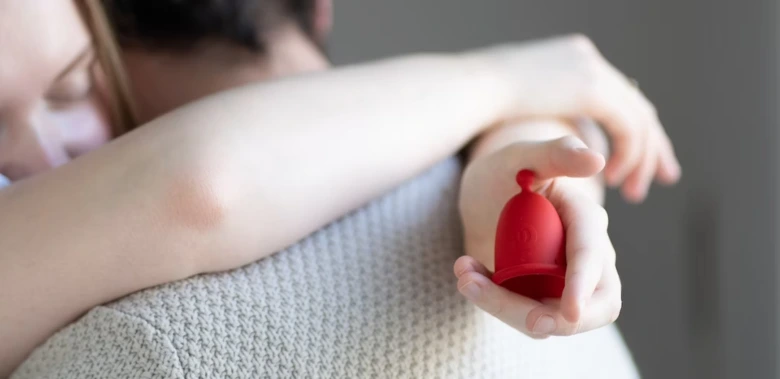 Žena drží červenou menstruační houbu v ruce.