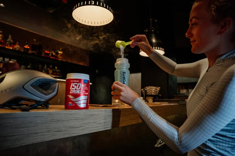 Žena míchá nápoj pro sportovce v šejkeru na baru.