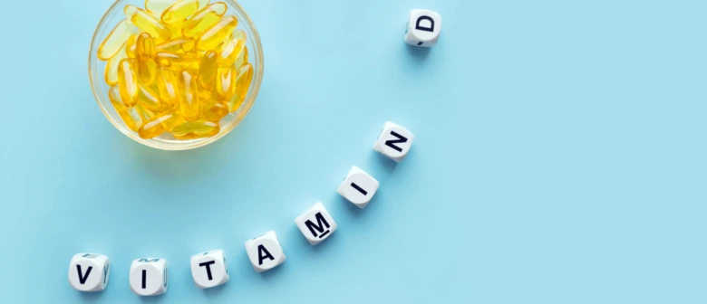 Sklenice žlutých vitamínových kapslí s písmeny VITAMÍN D na modrém pozadí.