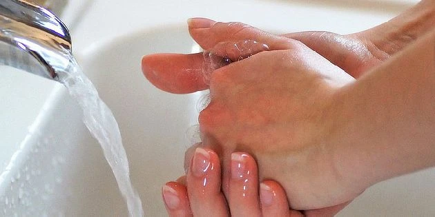 Ruční mytí pod tekoucí vodou v umyvadle.