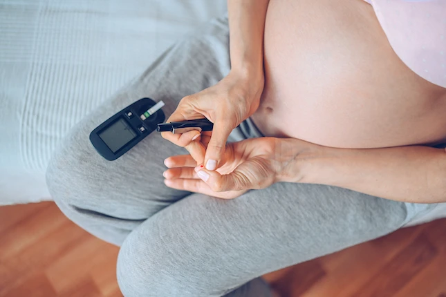 Těhotná žena měří hladinu cukru v krvi pro diagnostiku cukrovky.