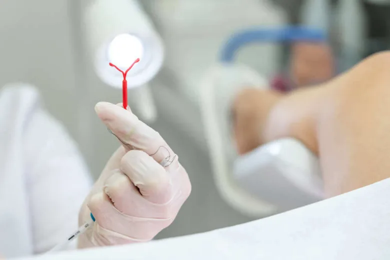 Rukou v rukavicích se drží nitroděložní tělísko s krví.