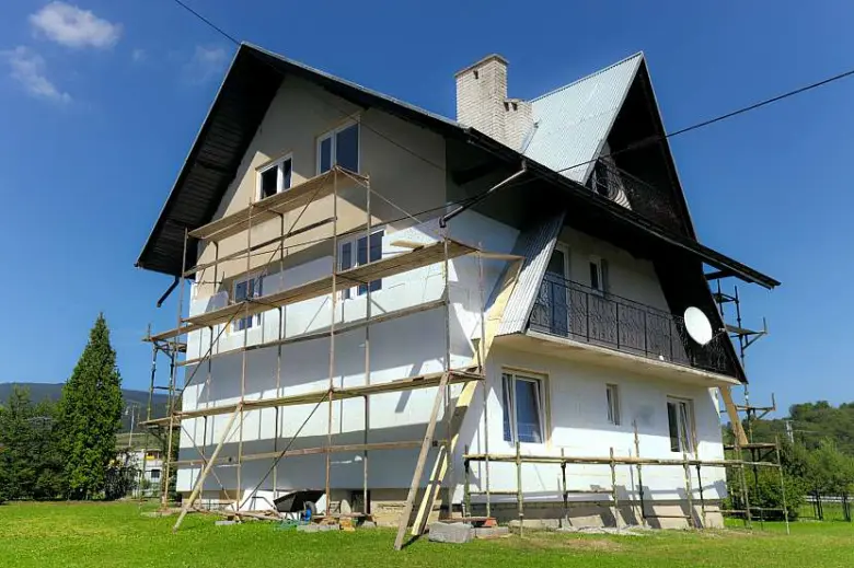 Dřevěná chata s oporou pro zateplování fasády na slunci.