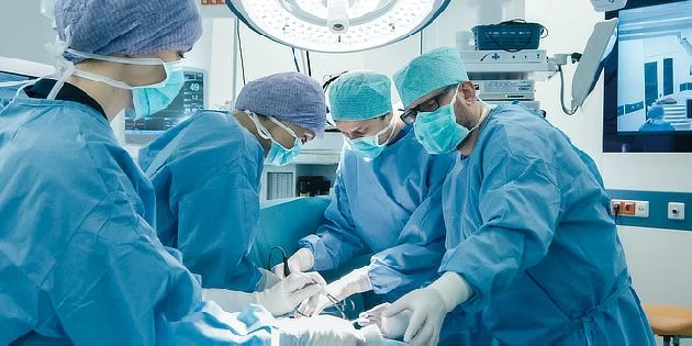 Tým chirurgů operuje dítě v operační sále.