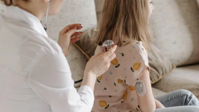 Zdravotnický pracovník léčí pacientku s glukometrem na paži.