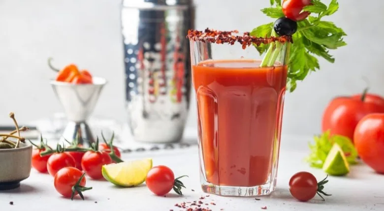 Koktejl Bloody Mary s okurkou a rajčaty na bílém pozadí.