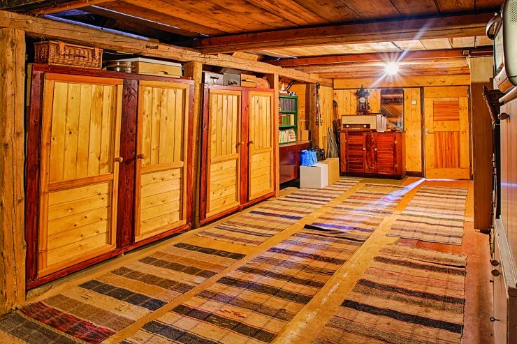Vnitřek dřevěné chalupy s podlahovými koberci a skříňmi.