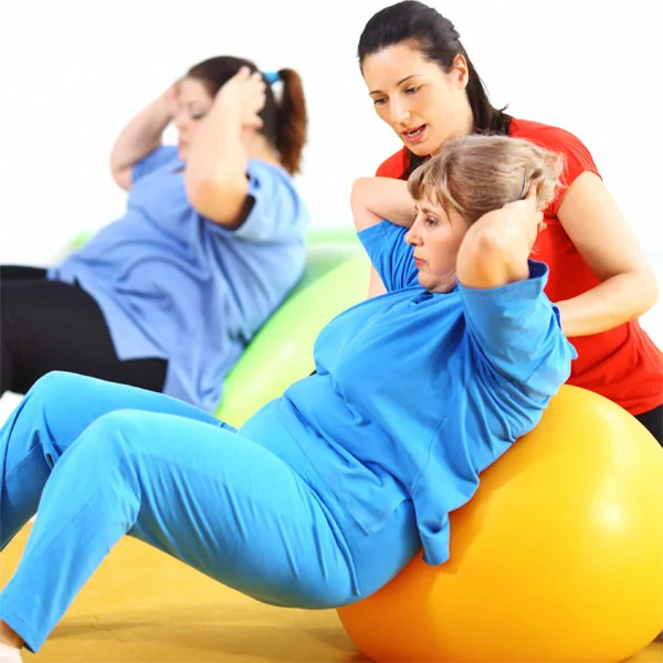 Trénink s fitnes trenérem na cvičicím míči pro hubnutí.