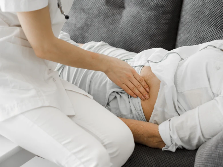 Lékař prohmatuje břicho pacienta při vyšetření bolesti.