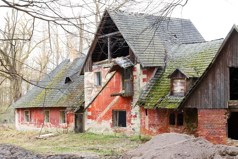 Zanedbaná červená cihlová chalupa v přírodě připravená na opravu.