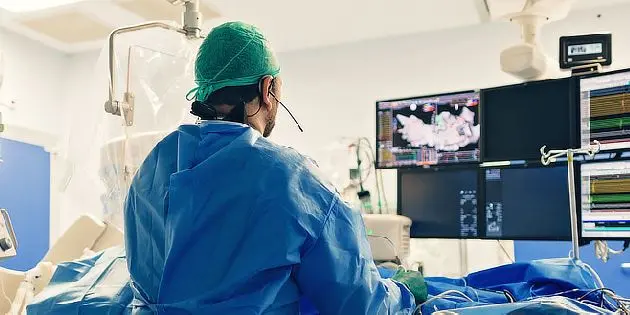 Chirurg v operační místnosti pracuje na pacientovi s monitorováním.