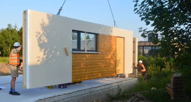 Stavebníci montují prefabrikovaný stěnný prvek pro rodinný dům.