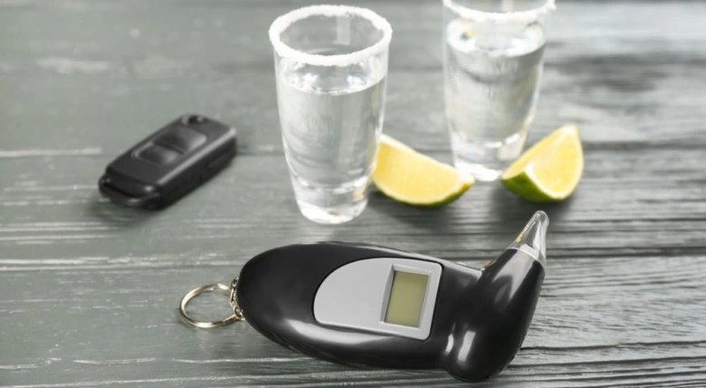 Testovací přístroj na dech s klíči od auta a skleničkami alkoholu.