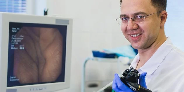 Lékař s endoskopem u monitory zobrazujícího střevní stěnu.
