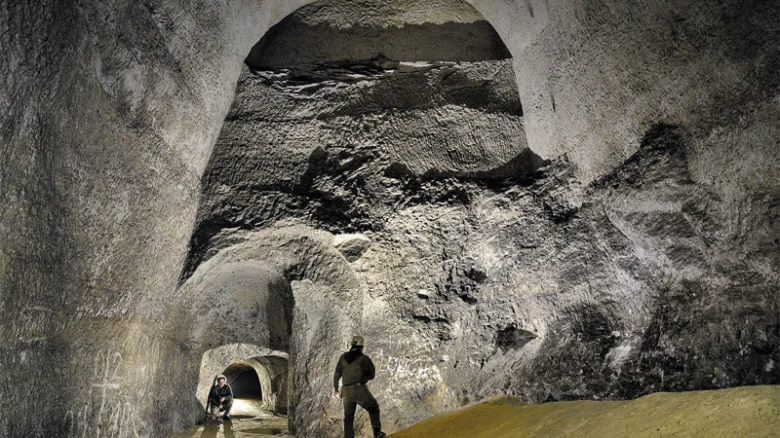 Dva lidé v obrovské podzemní jeskyni nebo tunelu.