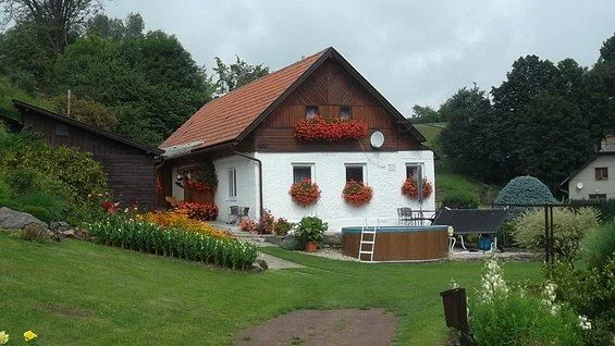 Rodinný dům s zahradou a květinovými okny v českém prostředí.
