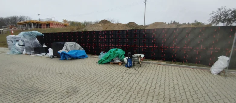 Staveniště pro monolitickou opěrnou zeď s černými bloky.