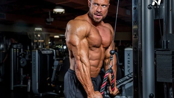 Muž cvičí na káblu pro posílení biceps v tělocvičně.