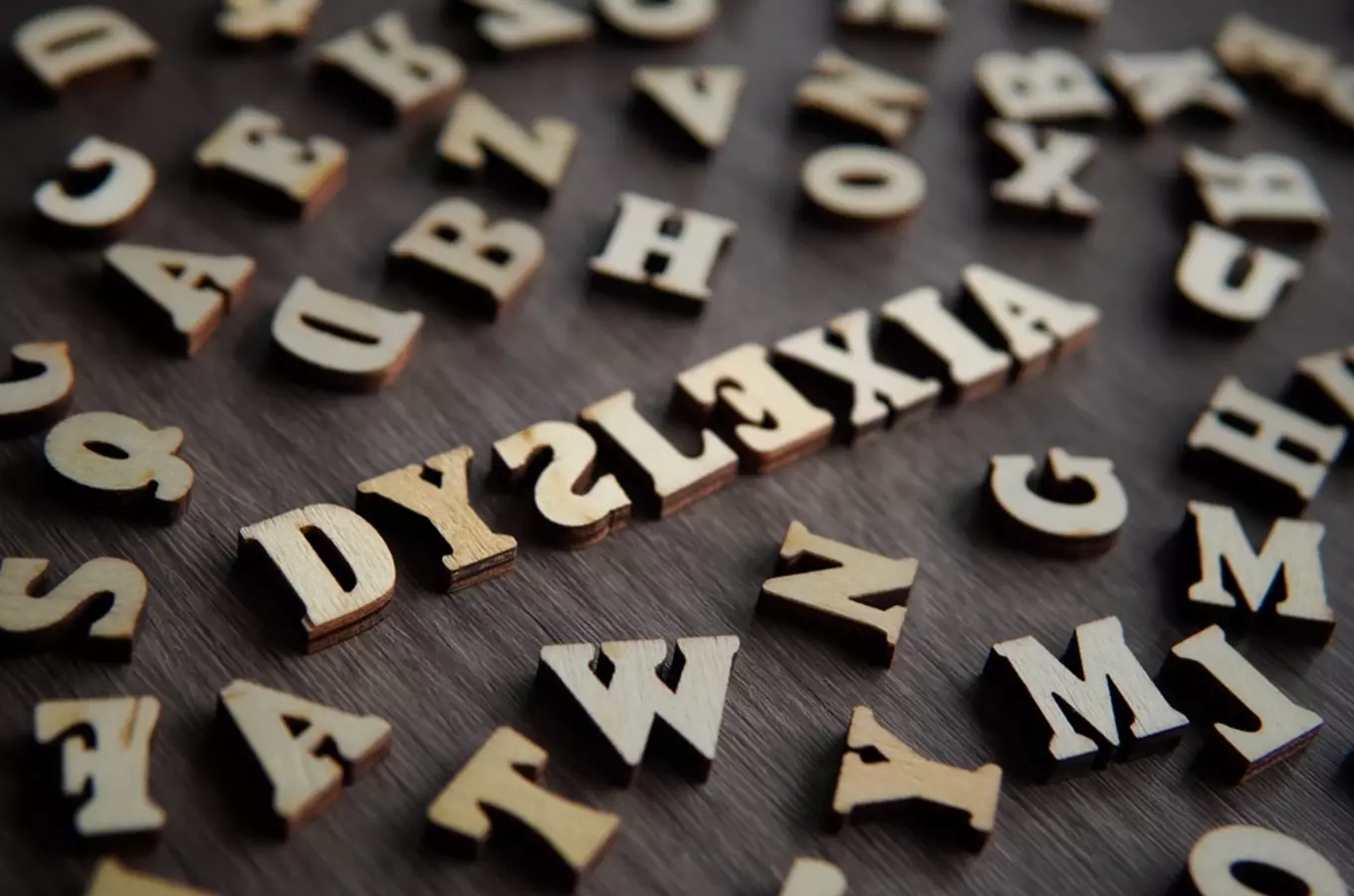 Dřevěné písmena slova dyslexie na tmavém povrchu.