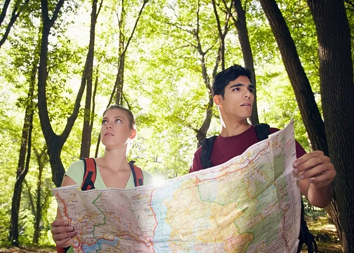 Muž a žena hledají cestu v lese s mapou.