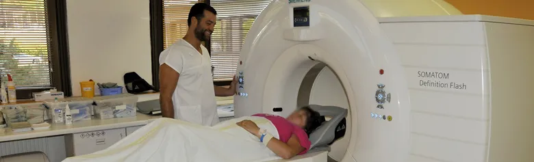 Pacientka leží v tomografu při vyšetření pod dohledem lékaře.