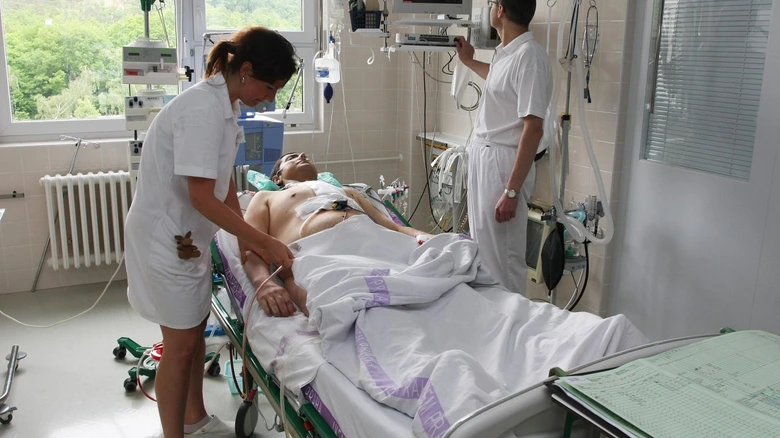 Nemocnice: lékařka ošetřuje pacienta na lůžku s monitorováním.