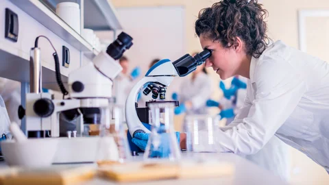 Vědec zkoumá vzorek pod mikroskopem v laboratoři.