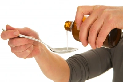 Person pouring liquid medicine into spoon