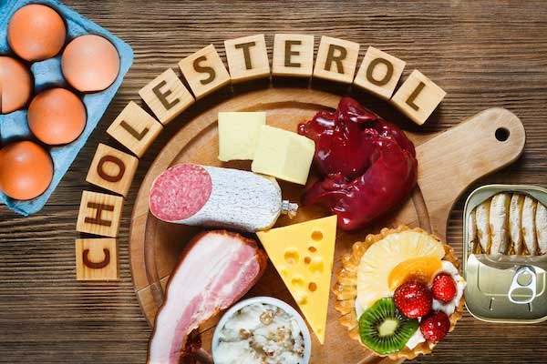 Různé potraviny s vysokým obsahem cholesterolu na dřevěném talíři.