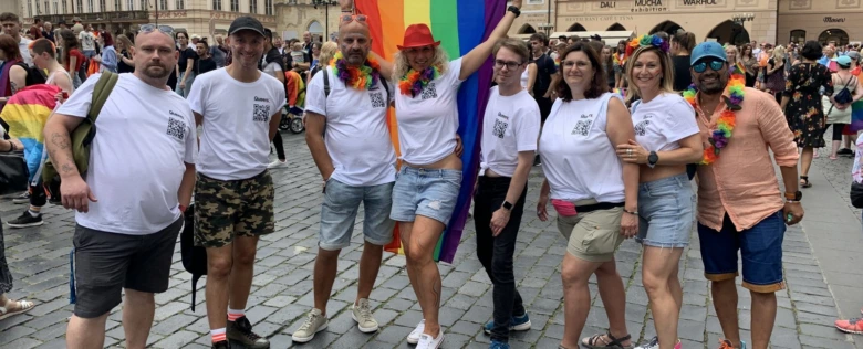 Skupina lidí na hrdosti s duhou vlajkou.