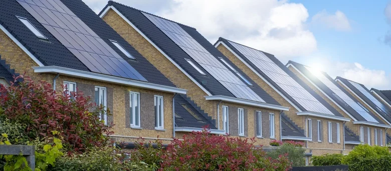 Řada domů s fotovoltaickými panely na střechách.