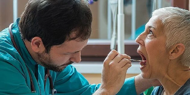 Lékař zkoumá ústní dutinu pacientky pro podezření na rozštěp rtu nebo patra.
