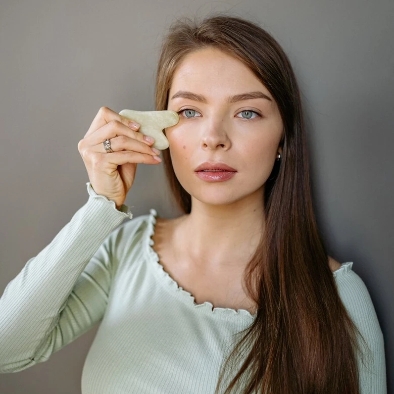 Žena používá masážní kámen na obličej pro hubnutí.