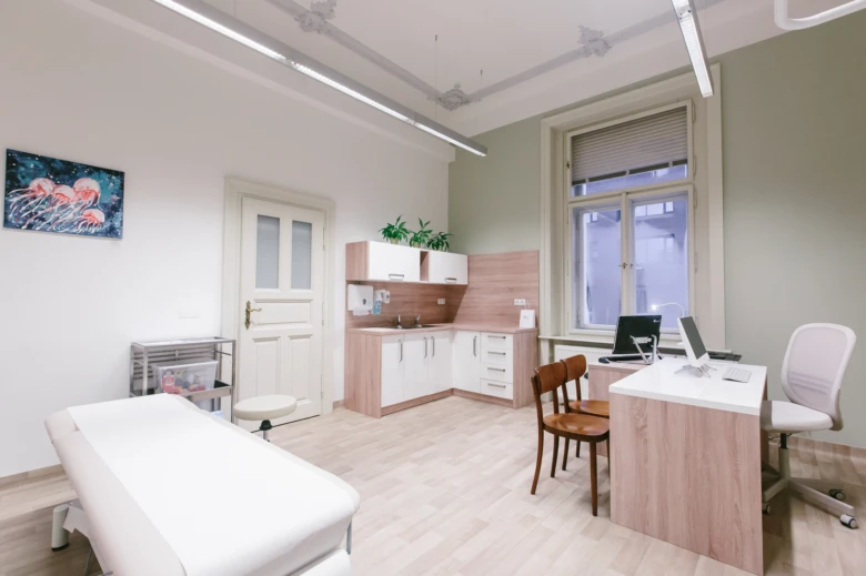 Moderní lékařský ordinace s vyšetřovacím stolem a pracovištěm.